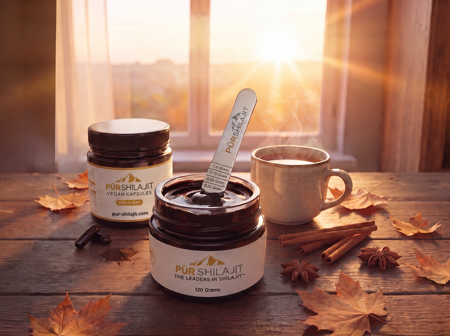 P&uuml;r Shilajit 120g resin jar with the engraved measuring spoon, Daily Drive capsules and a warm cup on an autumn table